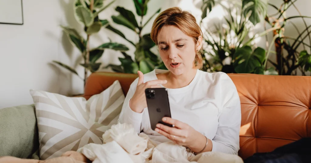 Femme consultant son téléphone tout en réfléchissant au coût d’une sortie.